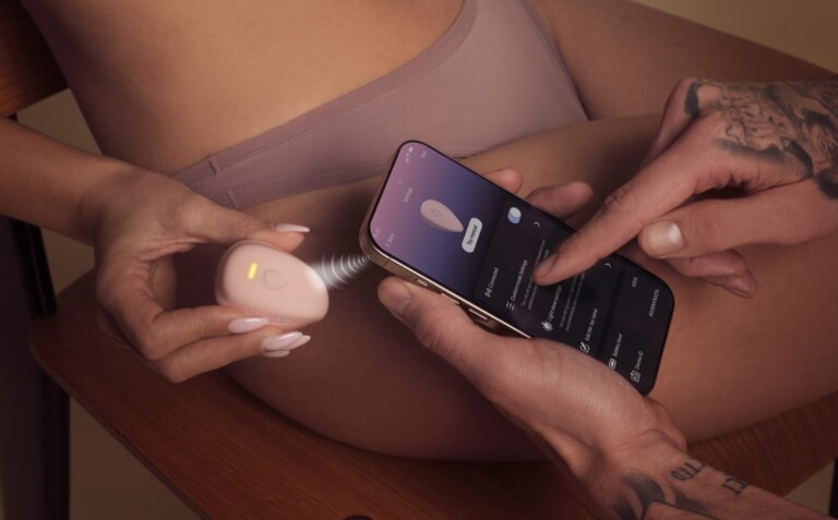 Deux mains règlent un vibromasseur LuxHer rose depuis une appli