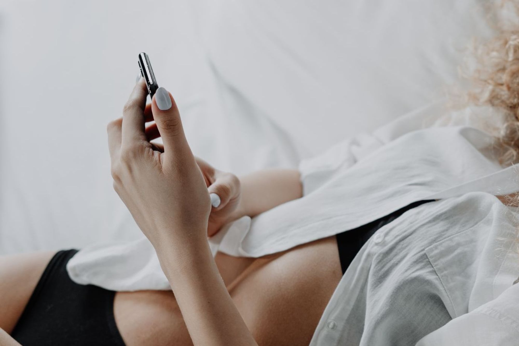 In black underwear in bed, phone in hand, waiting for his message