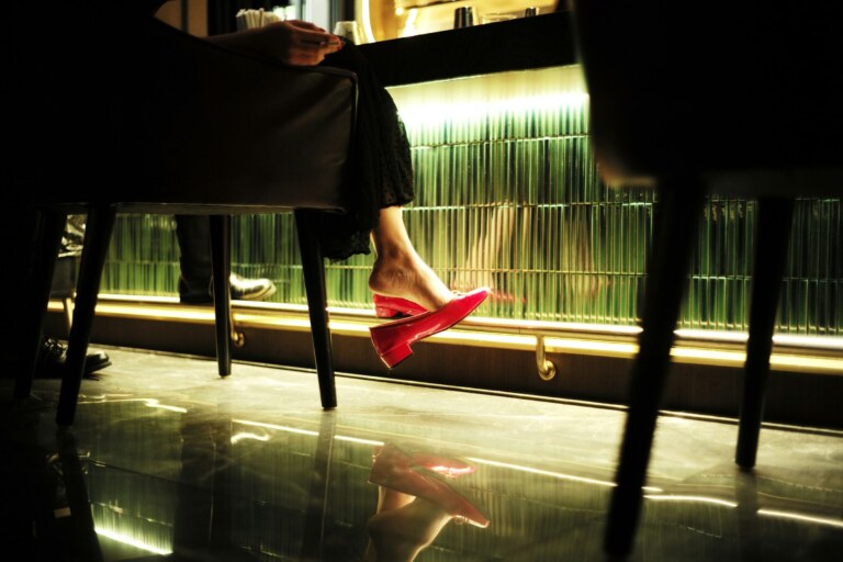 Red heels under a bar table at night